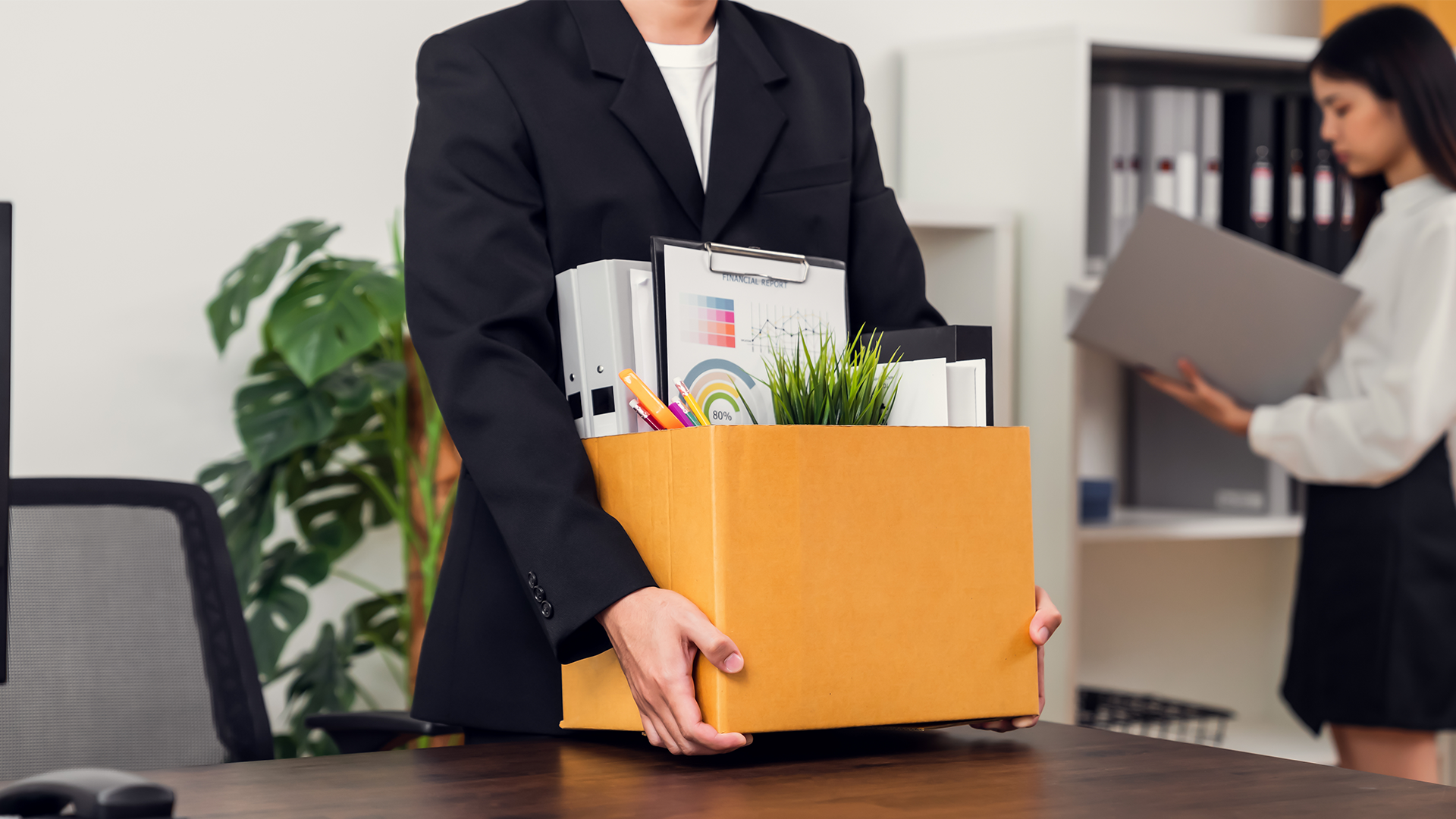 Individual carries box of belongings from office after resigning from an unhappy workplace