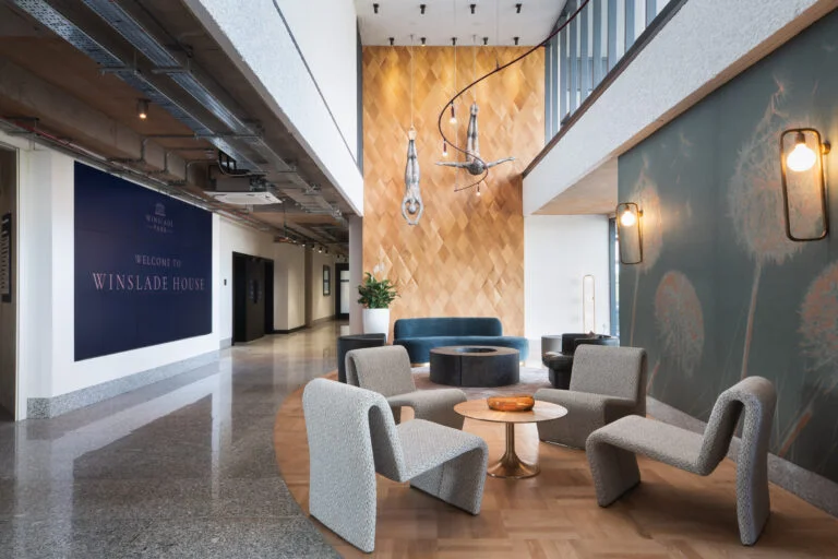 An image of the Winslade House reception with stylish seating area and wall mounted divers suspended over head behind modern led lighting