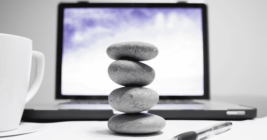 a pebble totem sits in front of a computer, representing office feng shui