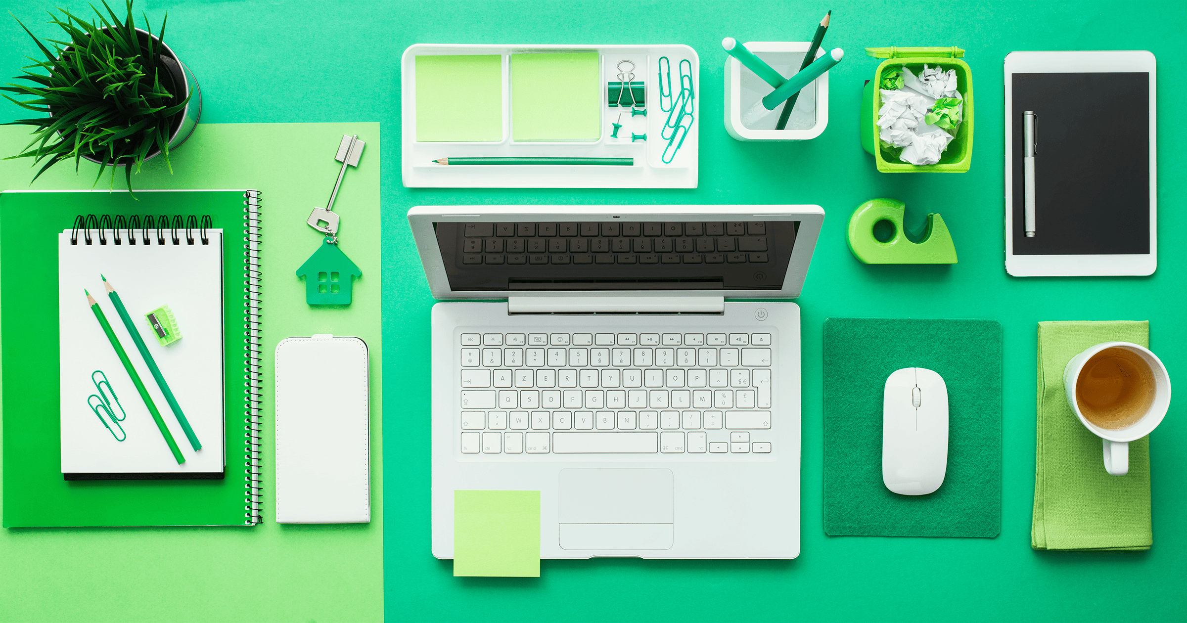 A birds eye view of a green desk with an assortment of stationary placed in a highly organised and aligned manner for Feng Shui