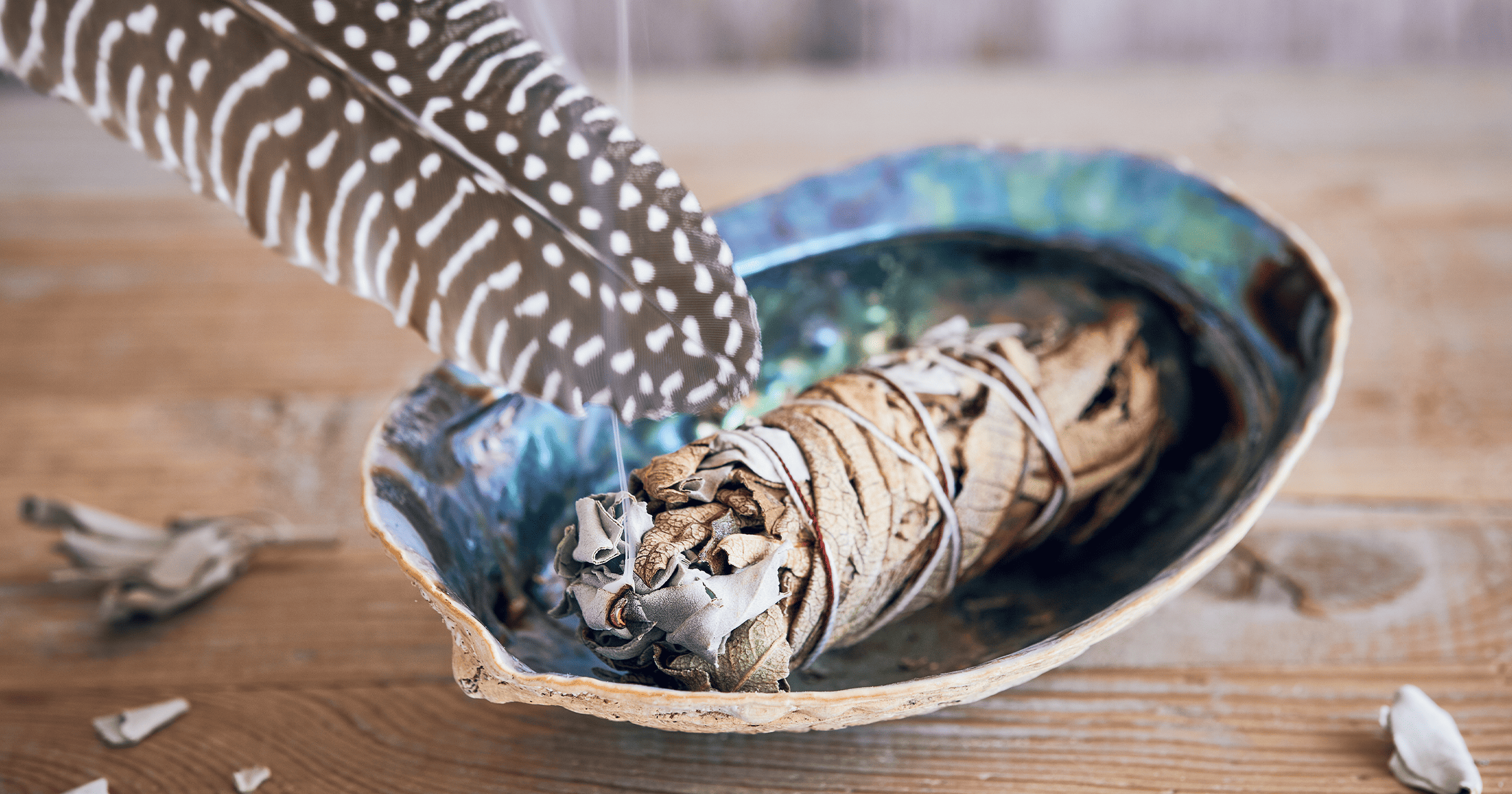 A traditoinal sage smudge stick lays in an ornate blue dish gently smoking ahead of being used to cleanse a space for Feng Shui